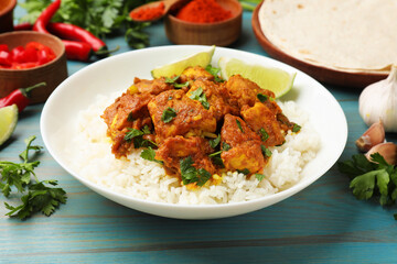 Delicious chicken tikka masala with rice, parsley, lime and spices on light blue wooden table, closeup