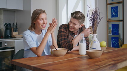 Laughing couple enjoying breakfast in sunny kitchen. Closeup happy family talk