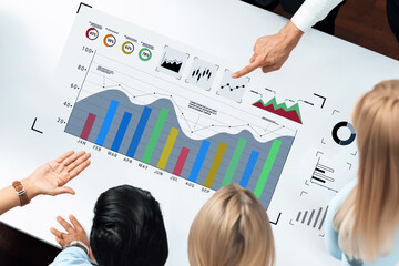 A diverse team engages in a business meeting, analyzing graphs and charts displayed on a modern workspace table, focusing on data-driven decision making. Trope