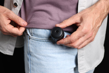 Man with hidden spy camera in his pocket on black background, closeup