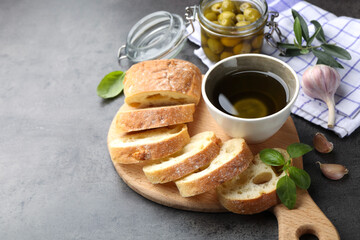 Slices of ciabatta, spices and olives on grey table, closeup. Space for text
