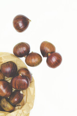 Chestnuts on a white background and paper bag,  zenith view. In vertical.