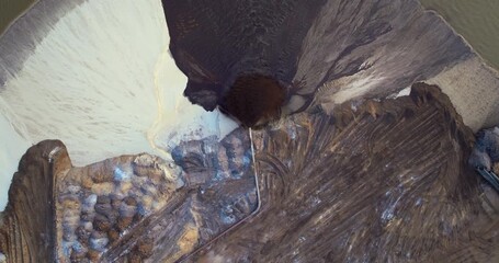 Aerial view of phosphate mining field with pipeline ejecting wet sand and mineral-rich slurry onto settling area.