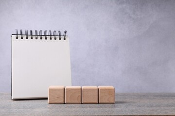 Blank cubes and notebook on wooden table. Mockup for design