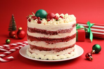 Delicious sponge cake with Christmas decor and berries on red background, closeup