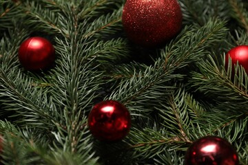 Beautiful spruce tree branches with Christmas ornaments as background, closeup