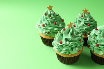 Christmas tree shaped cupcakes on green background, closeup. Space for text