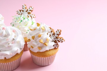 Tasty cupcakes with Christmas decor on pale pink background, closeup. Space for text
