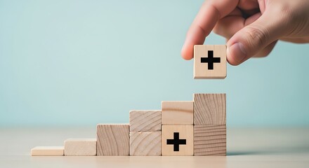 Hand stacking wooden blocks with plus signs to form a staircase