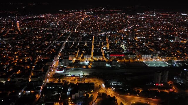 Breathtaking aerial footage capturing the sprawling urban landscape of mersin, turkey at night, with a grid of glowing streets, buildings, and city lights illuminating the dark sky