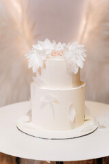White angel feather christening cake with sleeping baby topper pastel background