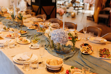 Elegant banquet table with blue hydrangea centerpieces and appetizers in warm restaurant