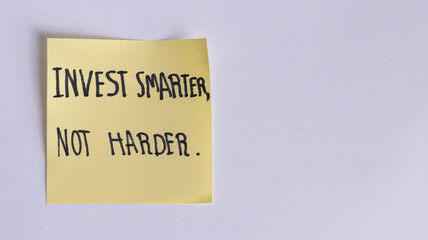 Motivational Financial Quote: INVEST SMARTER, NOT HARDER Handwritten on Yellow Sticky Note with White Copy Space