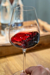 Hand swirling red wine in a glass, wine tasting