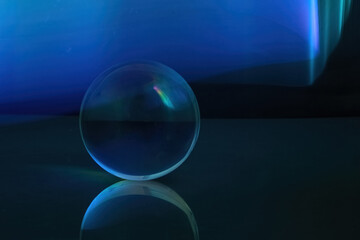 Blue Sphere Reflection. A transparent sphere on a reflective surface, set against a backdrop of deep blue hues