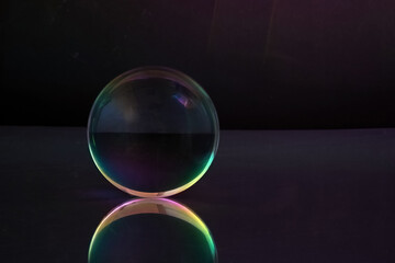 Ethereal Sphere. A glowing glass sphere with rainbow hues, reflecting on a sleek surface against a dark backdrop.