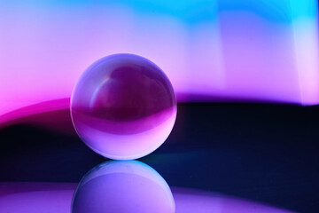 Mystical Orb. A glass sphere reflecting vibrant purple and blue hues on a smooth surface.