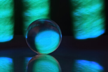 Glowing Orb Reflections. A glowing glass orb set against a backdrop of vibrant blue and green light.