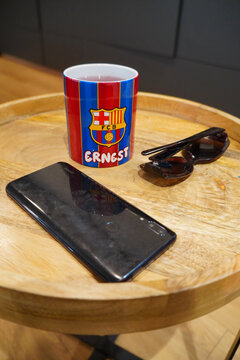 Still life with a FC Barcelona mug, sunglasses, and a smartphone on a wooden tray
