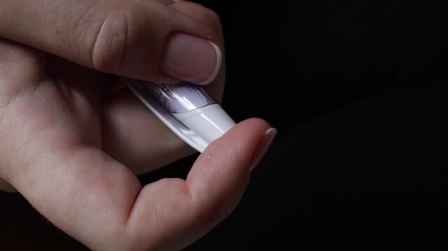 Clicking a ballpoint pen with fingers in a close-up view against a dark background