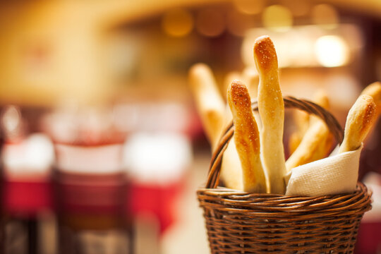 Golden, crispy breadsticks in a rustic basket, perfectly salted, on a warm, inviting restaurant table, delicious appetizer, Italian cuisine, snack, dining experience, gourmet food background