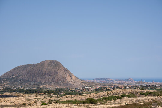 Serene mountain landscape with coastal city view under clear blue sky