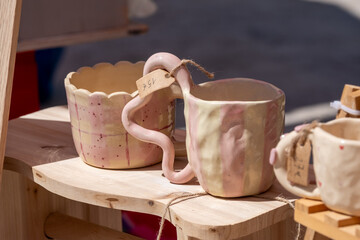 Unique handmade ceramic mugs with artistic handles on display at artisan market