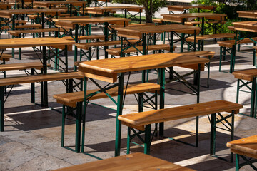 Outdoor wooden tables and benches in sunlit patio setting with metal frames