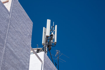 Modern urban communication infrastructure with cell tower against clear blue sky