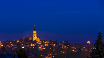 Obraz premium Mondaufgang über der Bergstadt Schneeberg im Erzgebirge bei Nacht.
