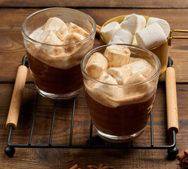 Hot chocolate with fluffy marshmallows on a wooden board.