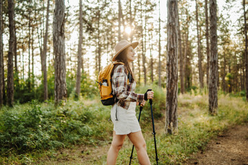 Young caucasian woman trekking or hiking through scenic forest during golden hour