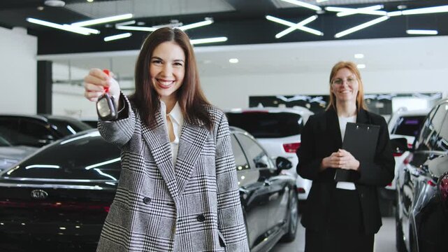 A portrait of a happy customer holding the keys to a new car, with a sales consultant in the background, signifying a successful consultation and a completed sale.
