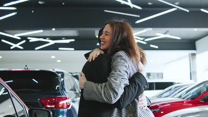 Saleswoman celebrates successful deal with client at automobile dealership during consultation and test drive