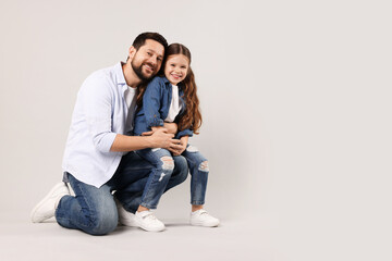 Happy father hugging his daughter on grey background. Space for text