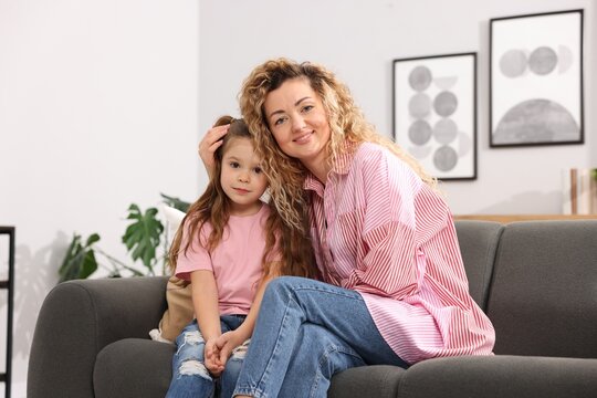 Happy mother hugging her daughter on sofa at home. Family bonding - Powered by Adobe