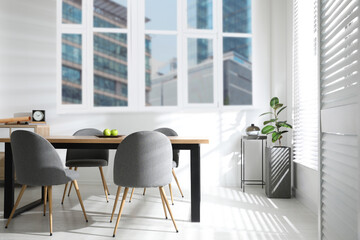 Table and chairs near windows in room. Interior design