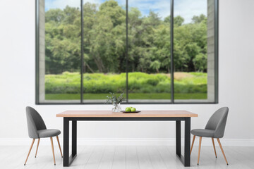 Table and chairs near large window in room. Interior design