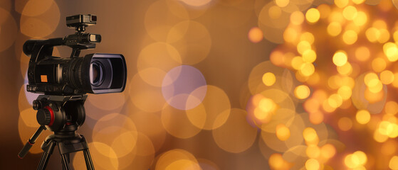 Video camera on stand against blurred lights, bokeh effect. Banner design