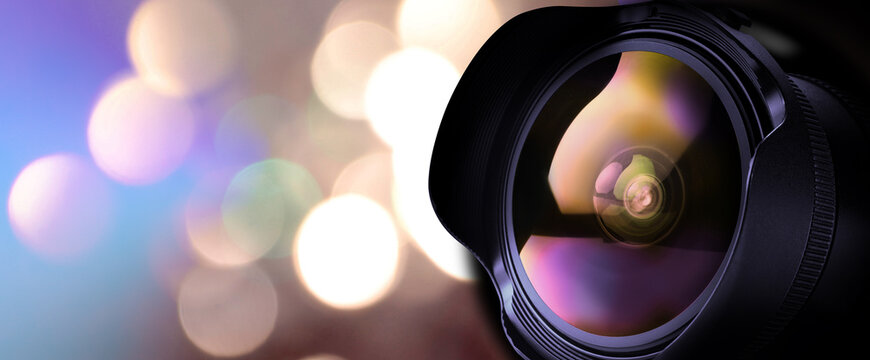 Camera lens against blurred lights, bokeh effect. Banner design
