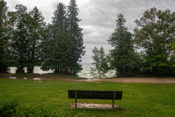 Fototapeta premium Cave Point offers a peaceful view of Lake Michigan on a rainy day with dark clouds above and lush trees surrounding the area