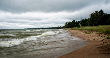Waves crashing on the sandy shores near  Cave Point along Lake Michigan on a cloudy day