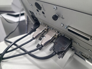 Connections at the back of a machine show multiple cables plugged in to power and communication ports