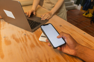 Customer making contactless payment using smartphone at counter