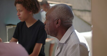 African American senior and teenager enjoying a family meal outdoors, showcasing connection and...