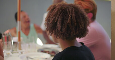 One Hispanic Latin teenager of African descent turning his head towards the camera during a family...