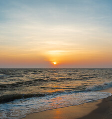 Obraz premium serene vertical image capture beauty sunset over calm ocean. sun low on horizon casting warm golden glow across sky and reflect off gentle wave. warm orange near creating peaceful calm atmosphere.