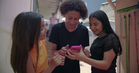 Teenagers gathered around a smartphone in suburban alleyway, sharing and enjoying social media...