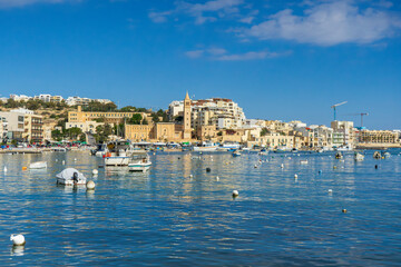 Marsaskala Malta coastal townscape boats on bright blue sea clear summer sky