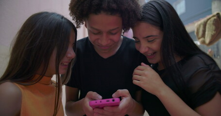 Teenagers laughing and reacting to funny video on smartphone in suburban alleyway, cheerful and...